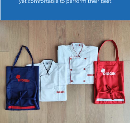 Custom embroidered restaurant aprons in navy and red with a matching double-breasted chef coat, branded 'Diggin'