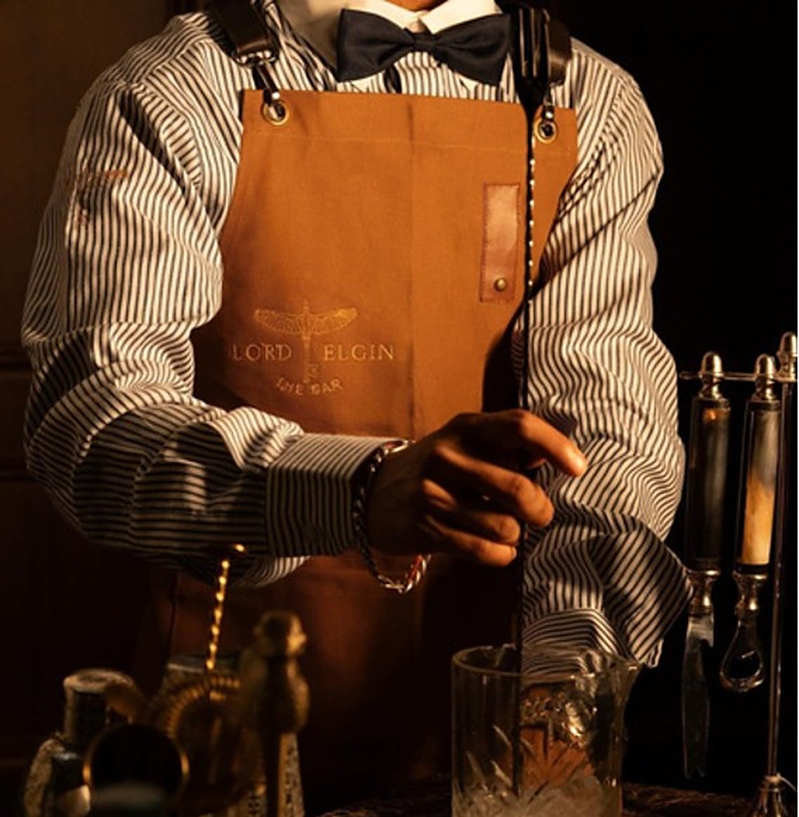Bartender at Lord Elgin, Ludhiana wearing a customized striped shirt and tan leather apron by RestroCart
